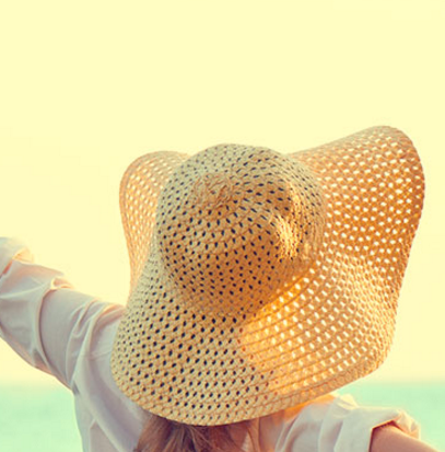 Woman wearing a sun hat facing towards the sun