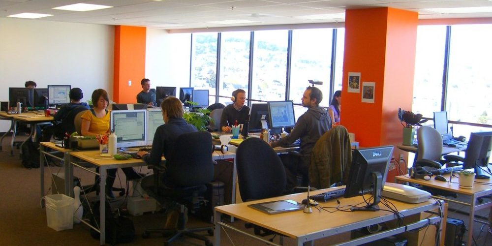 Workers at a marketing agency in an open office space with desks, compters, coffee mugs and supplies