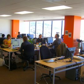 Workers at a marketing agency in an open office space with desks, compters, coffee mugs and supplies